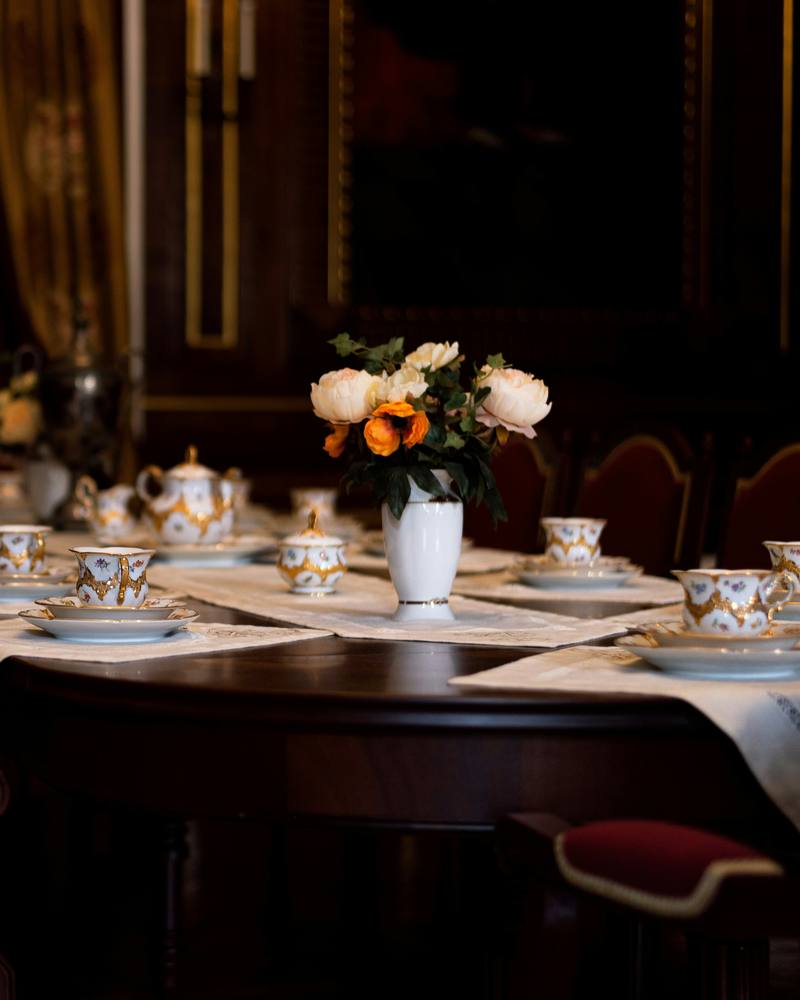 A long dining table laid with teacups and flowers