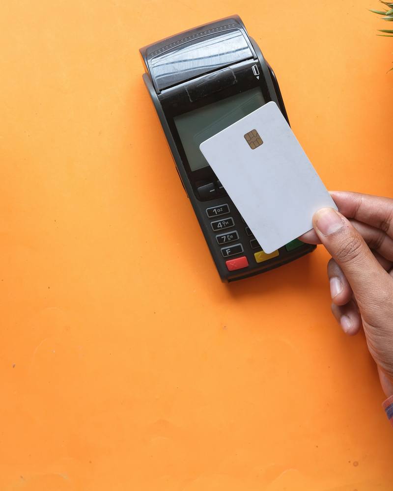 A hand tapping a card on a payment terminal